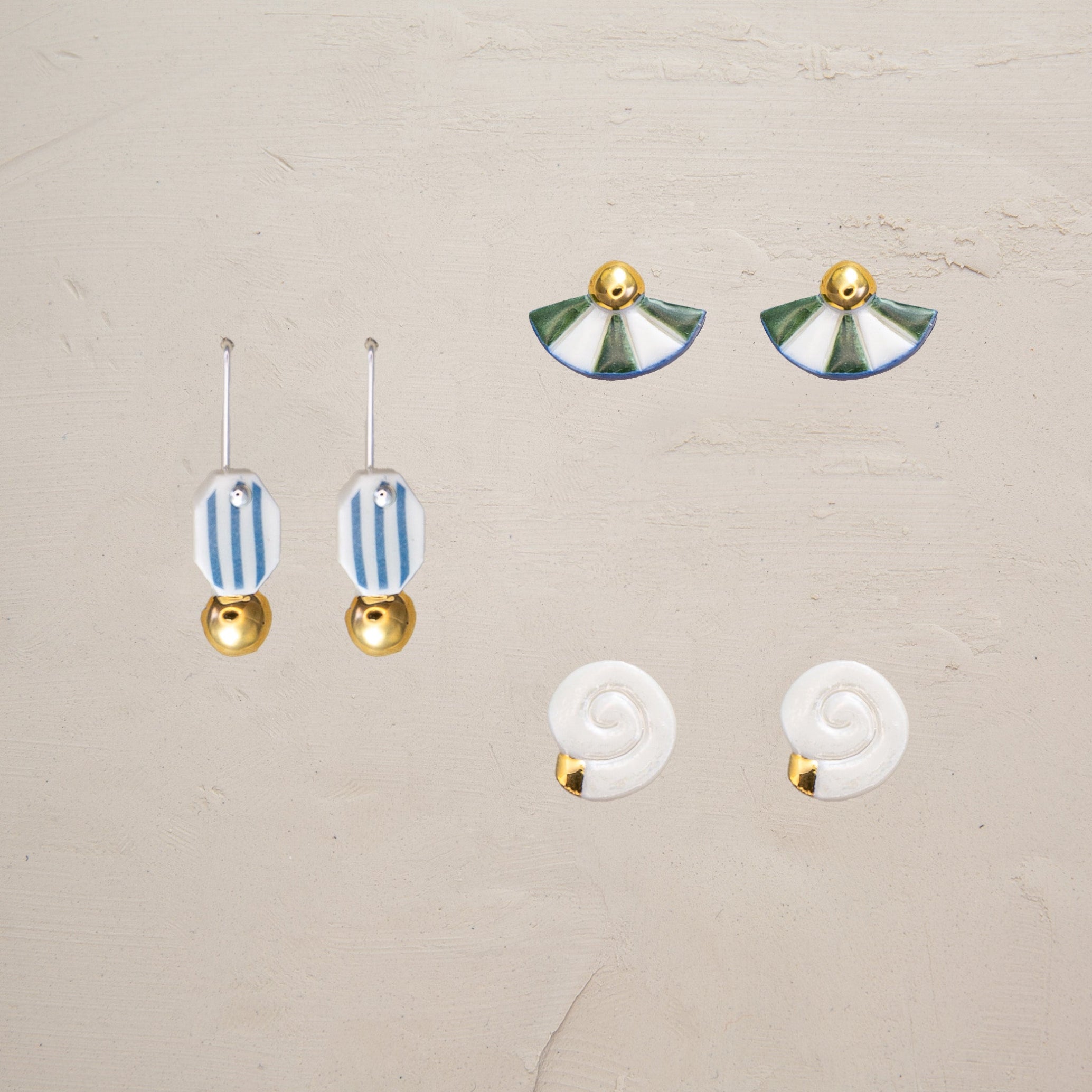 Set of earrings with blue and gold designs on a beige background